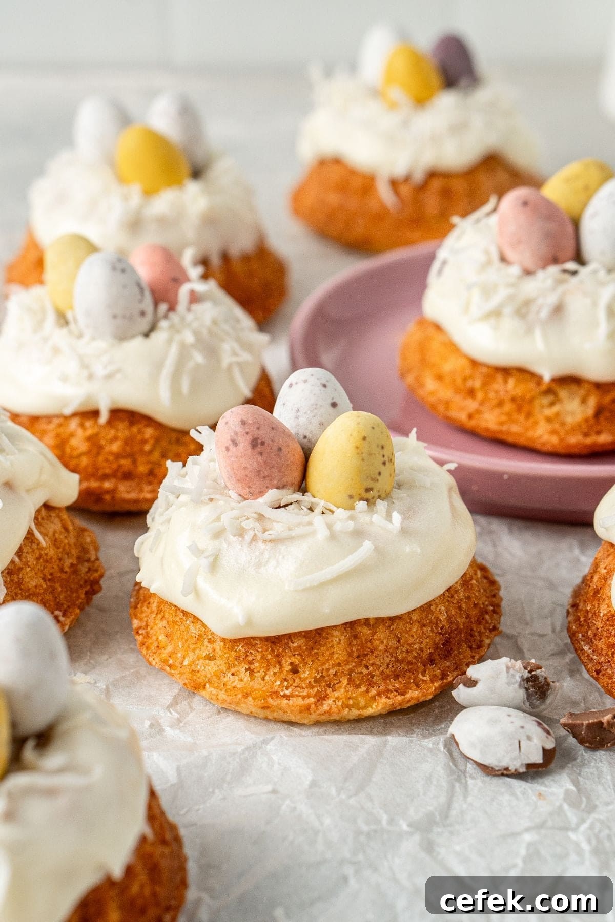 Mini Easter Bundt Cakes, topped with a cream cheese frosting, on some baking paper.