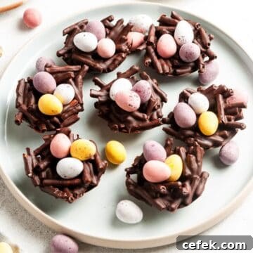 Round plate with Chocolate Pretzel Easter Nests, topped with mini eggs, with some mini eggs scattered around.