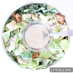 One bowl of Caesar salad with a small glass bowl of Caesar dressing with a spoon in the center.