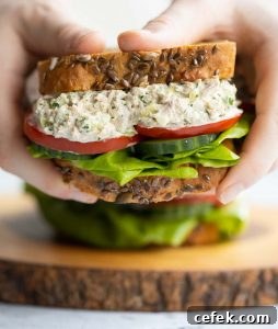holding sandwich close to camera with second sandwich blurred in background on wooden board