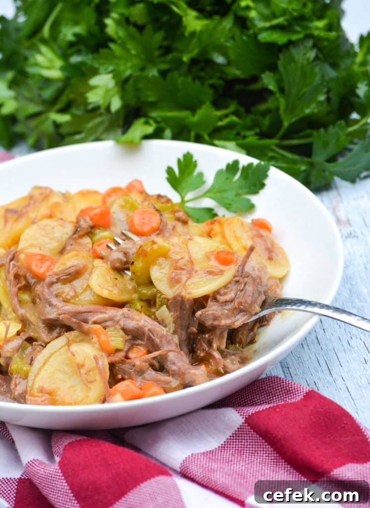 a silver fork digging into a white bowl filled with leftover pot roast casserole