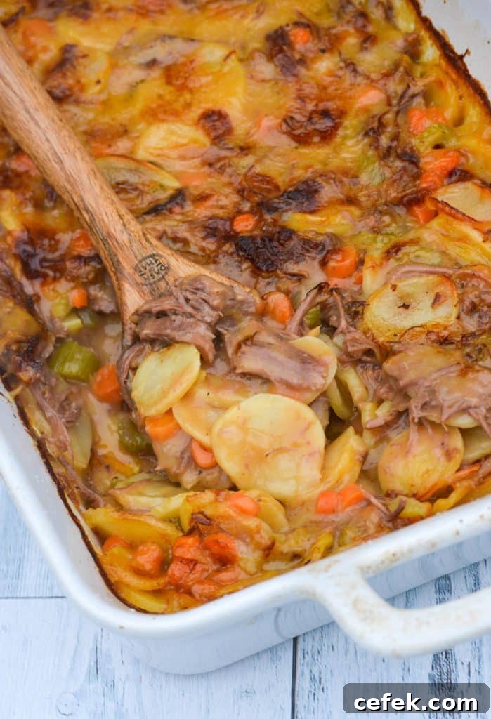 a wooden spoon digging into a white casserole dish filled with cheesy potatoes & leftover pot roast