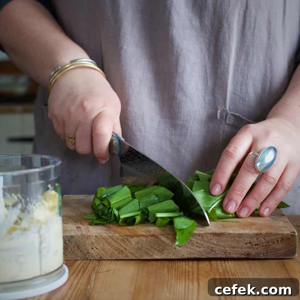 Woman's hands chopping fresh wild garlic leaves on a wooden chopping board