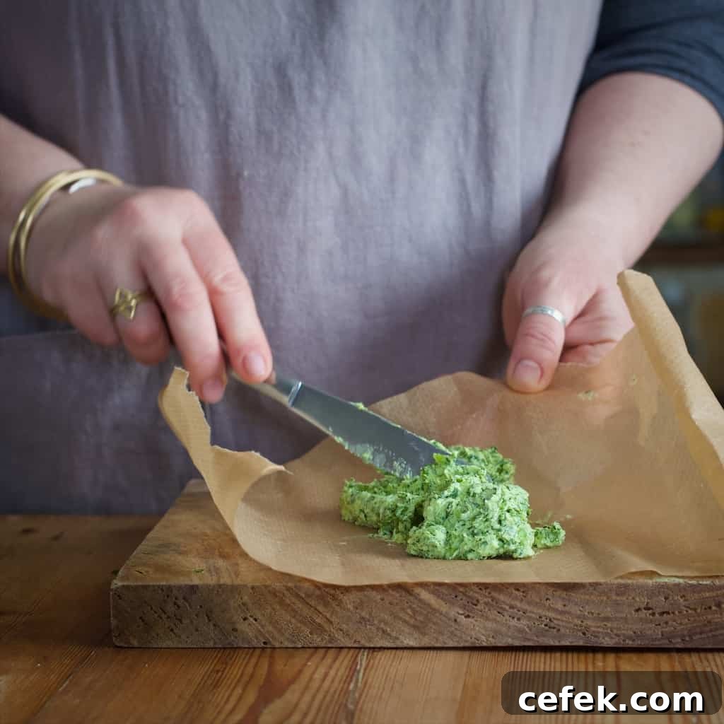 Woman's hand placing green wild garlic butter onto a brown piece of baking paper