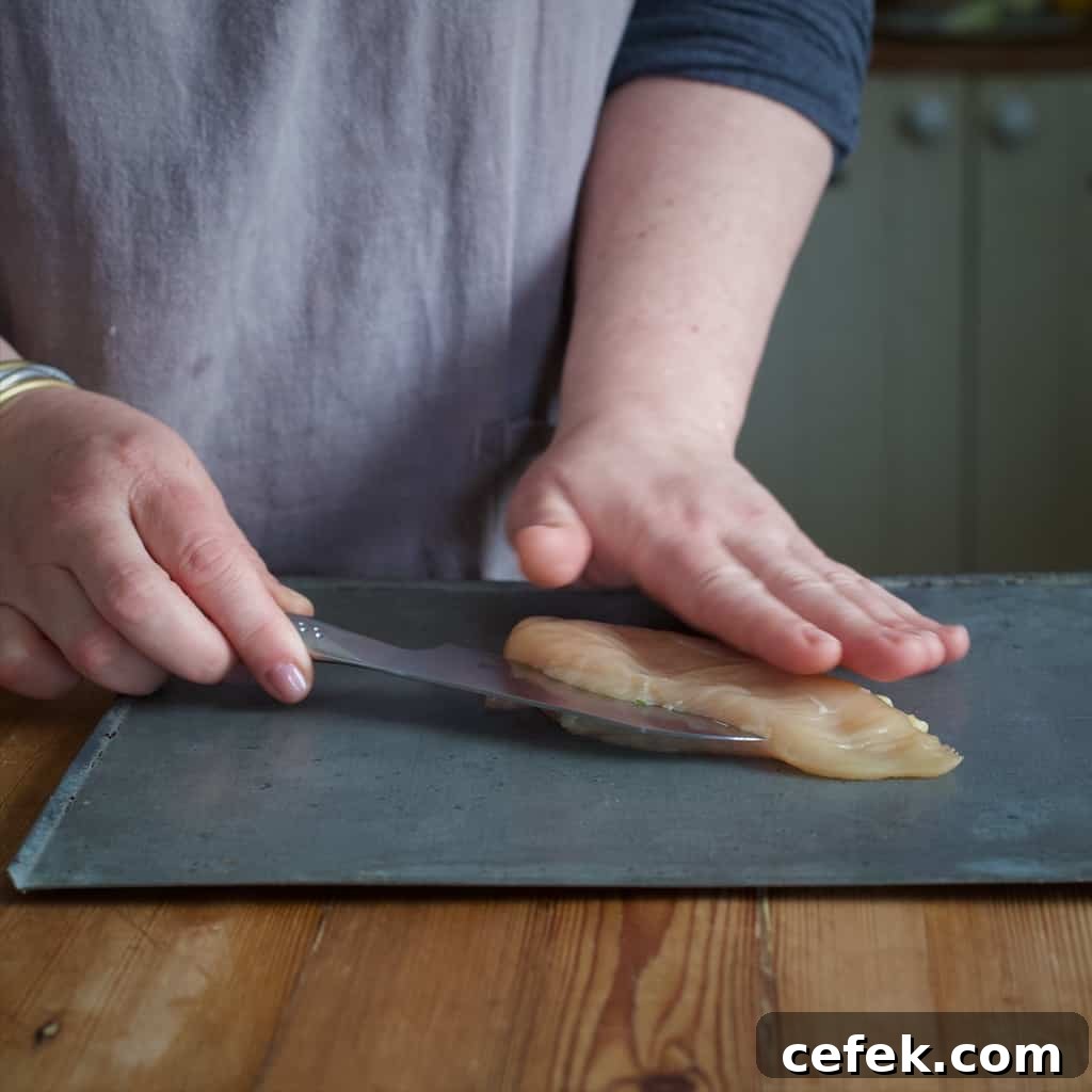 Woman's hands slicing a chicken breast in half with a sharp silver knife