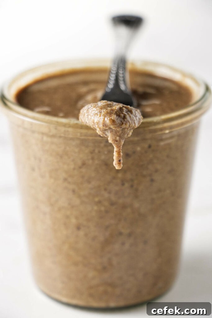 A jar of granola butter with a knife resting on the edge of the jar.