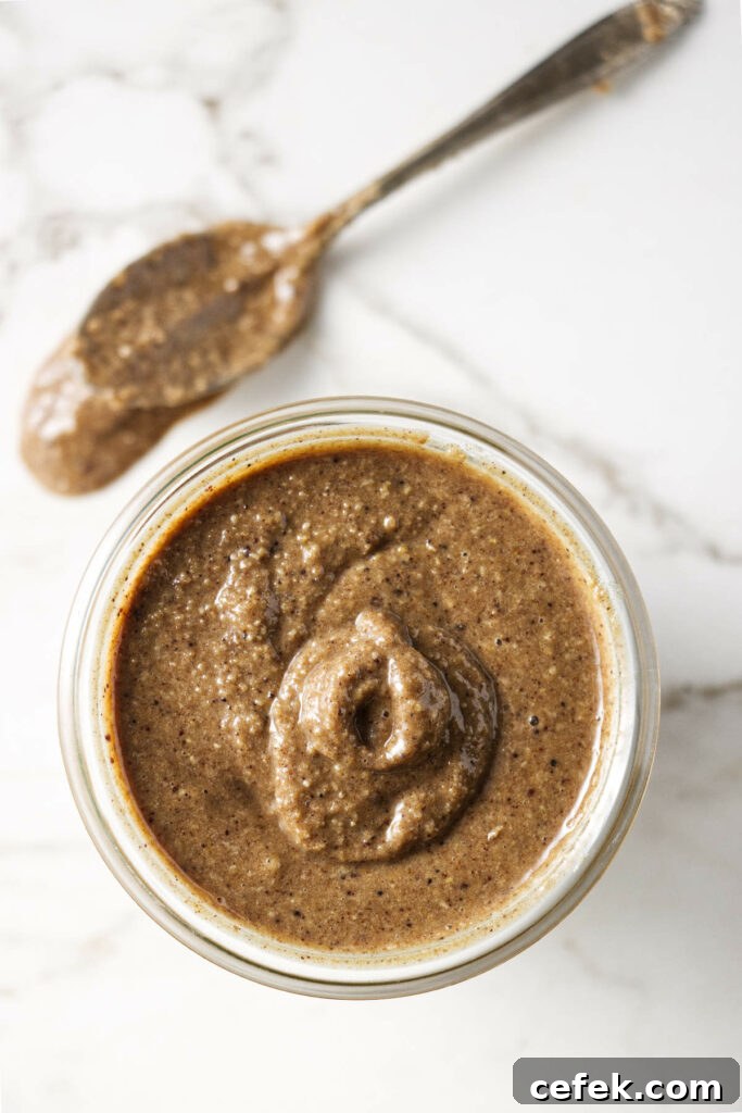 A spoon next to a jar of granola butter.