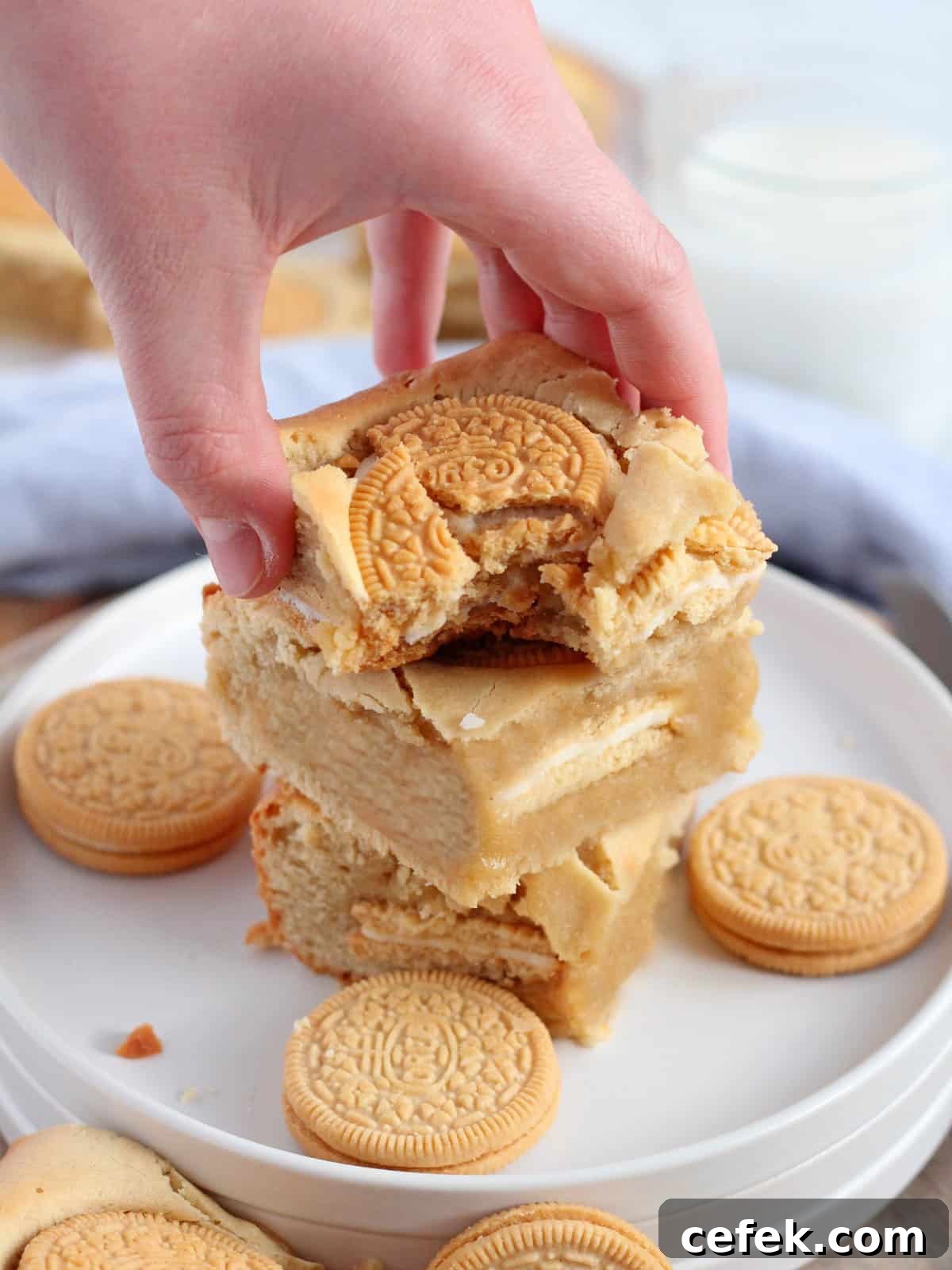 Golden oreo blondies bar in hand, with a bite, close up