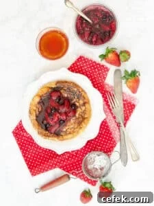 Matzo meal pancake on a white plate with fruit compote on top and tea on the side.