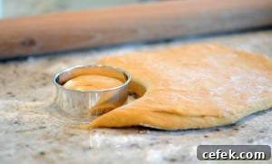 Cutting circle out of doughnut dough.