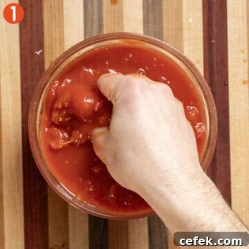 Hand crushing tomatoes.
