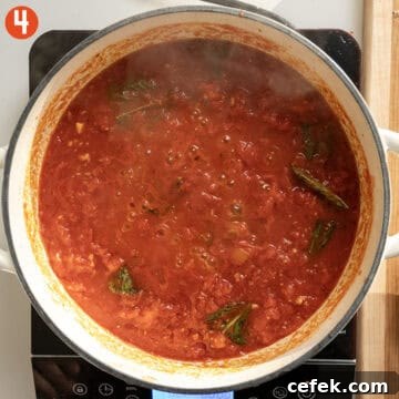 Simmering tomatoes and basil in a pan.