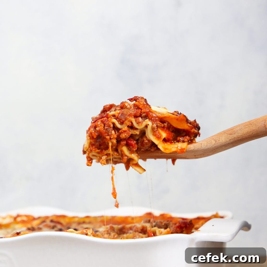 slice of lasagna on wooden serving utensil.
