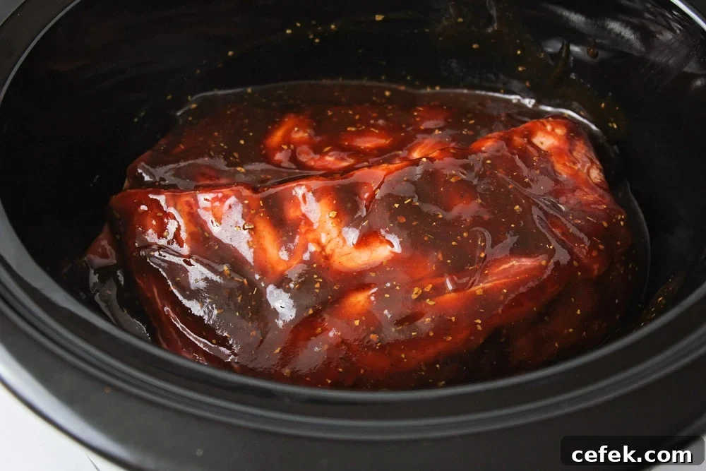 Ribs covered in sauce, cooking in the slow cooker.