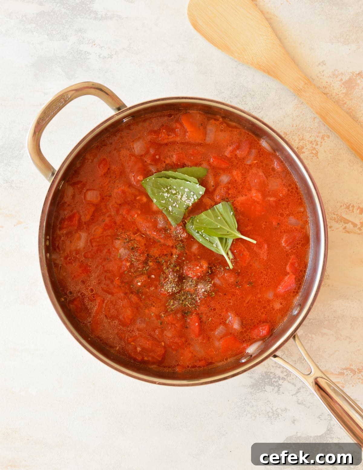 a skillet with pasta sauce, seasoning, and fresh basil