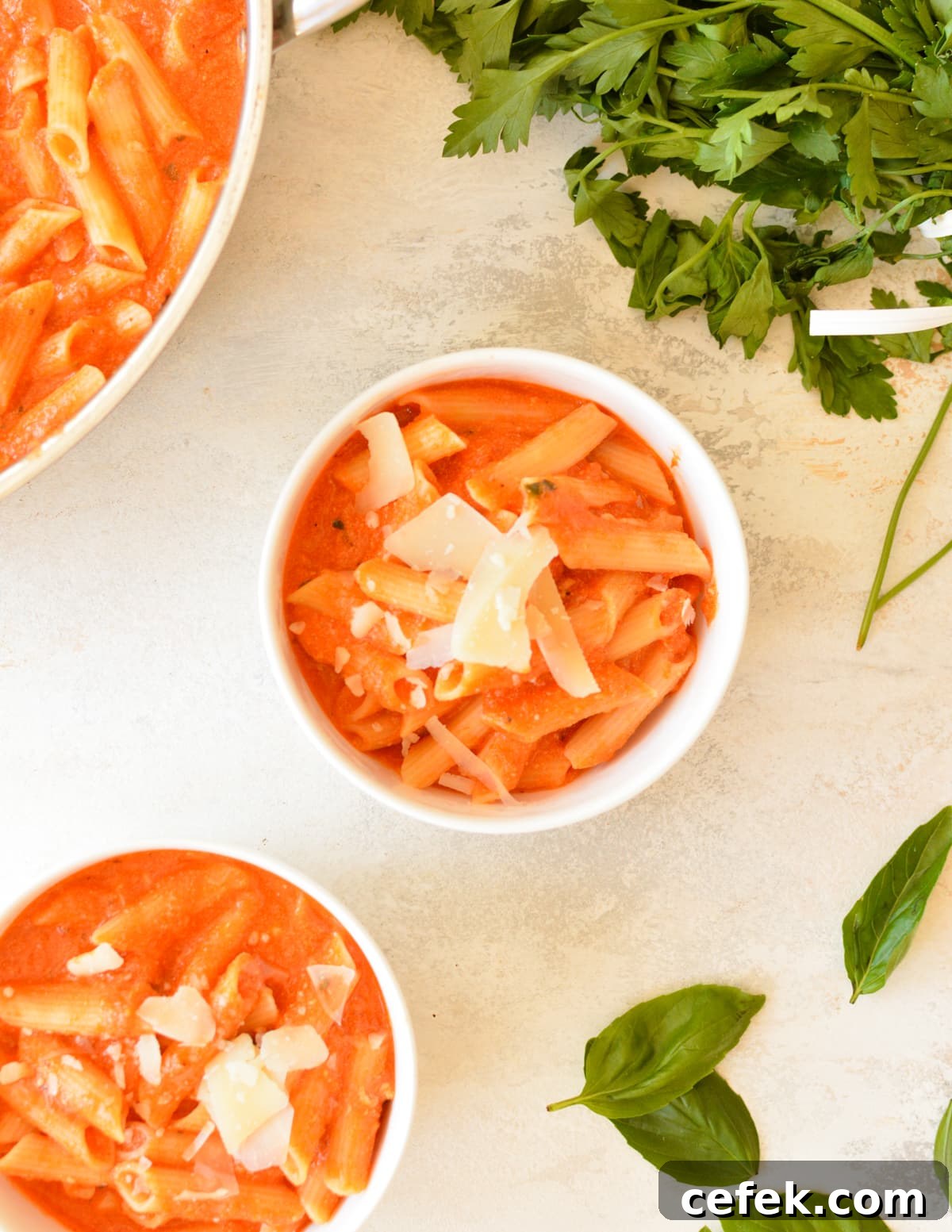 two bowls of pasta in pink sauce with parmesan