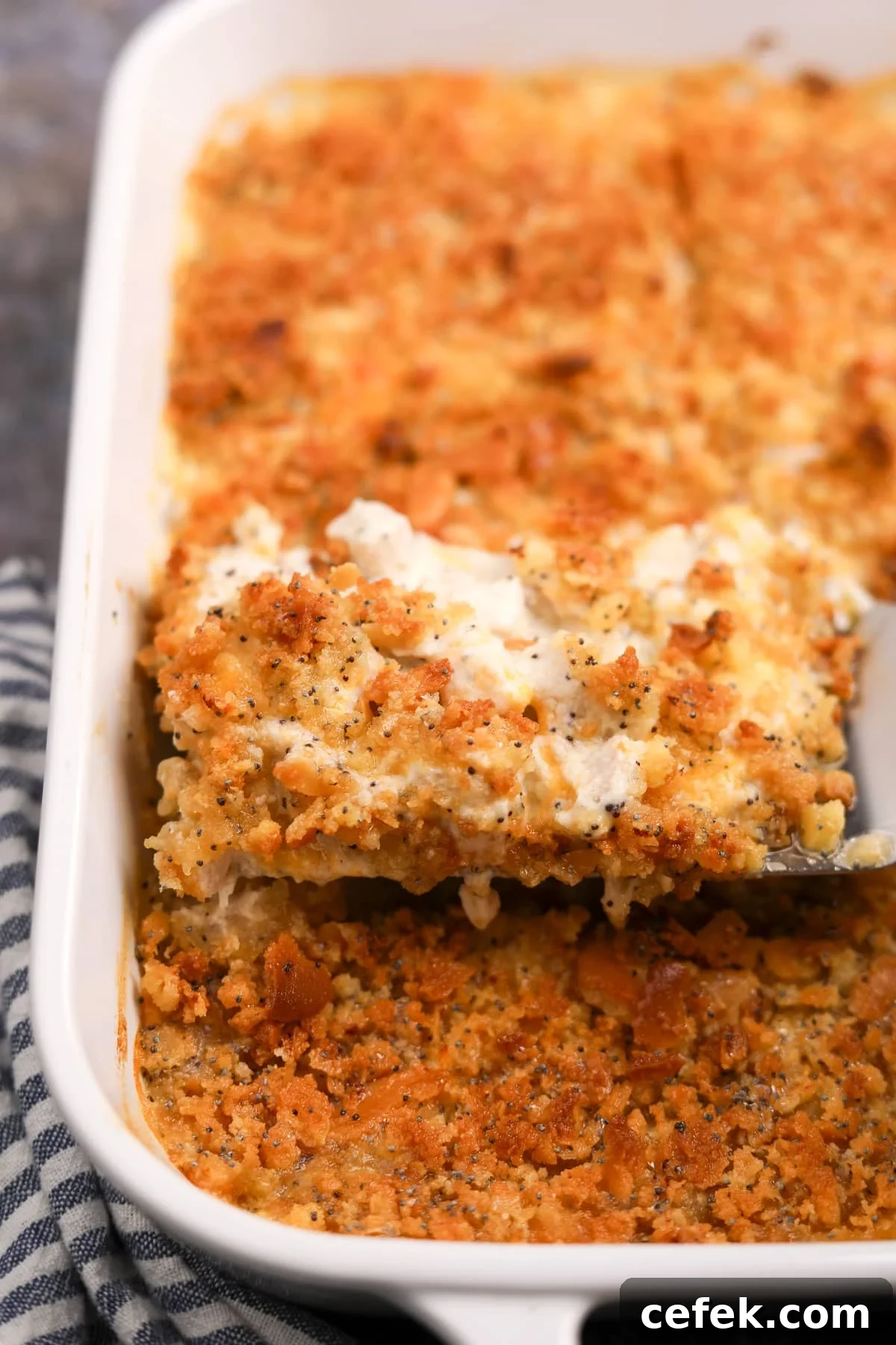 Lifting a portion of poppy seed chicken from a baking dish.