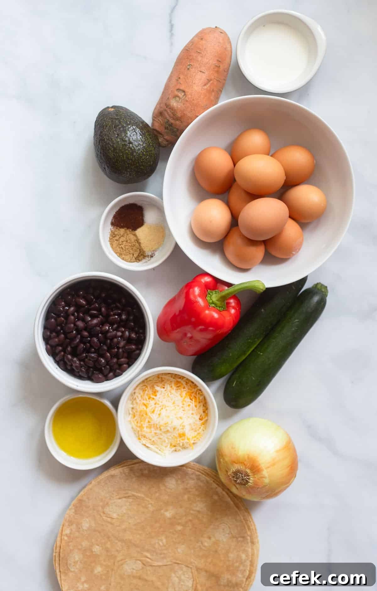 healthy breakfast burrito ingredients in white bowls on a white background. 