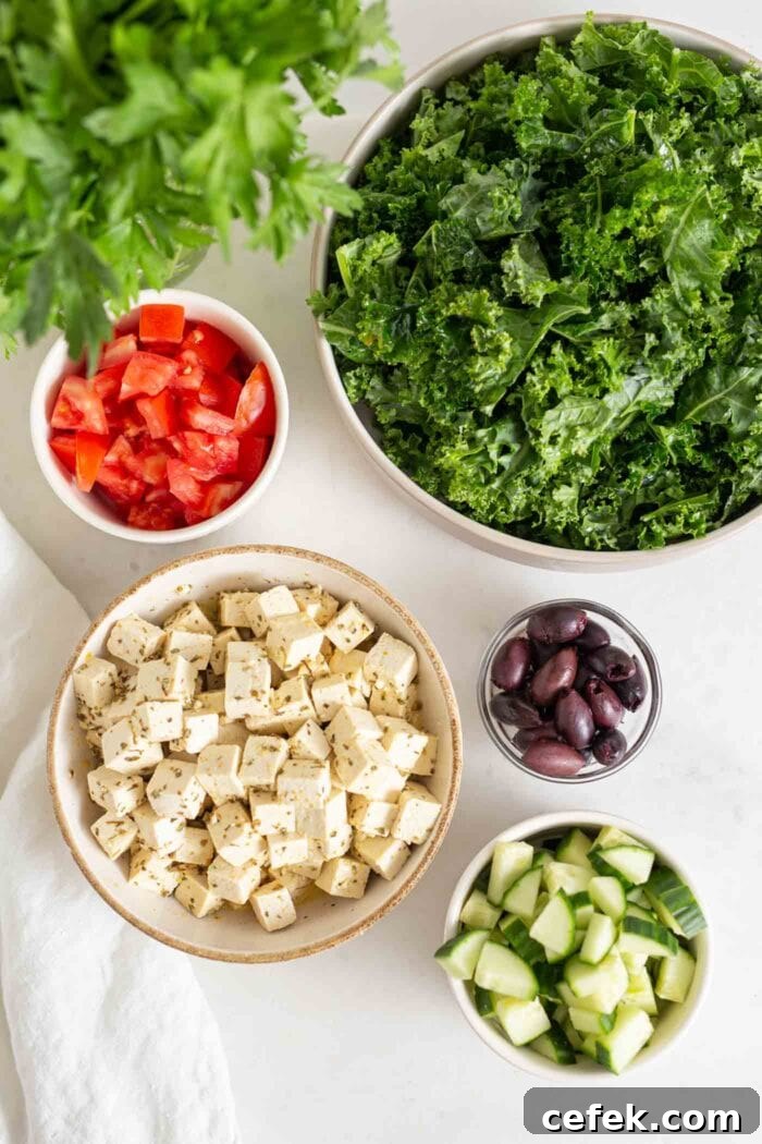 Tofu, olives, chopped kale, cucumber and tomato in bowls.