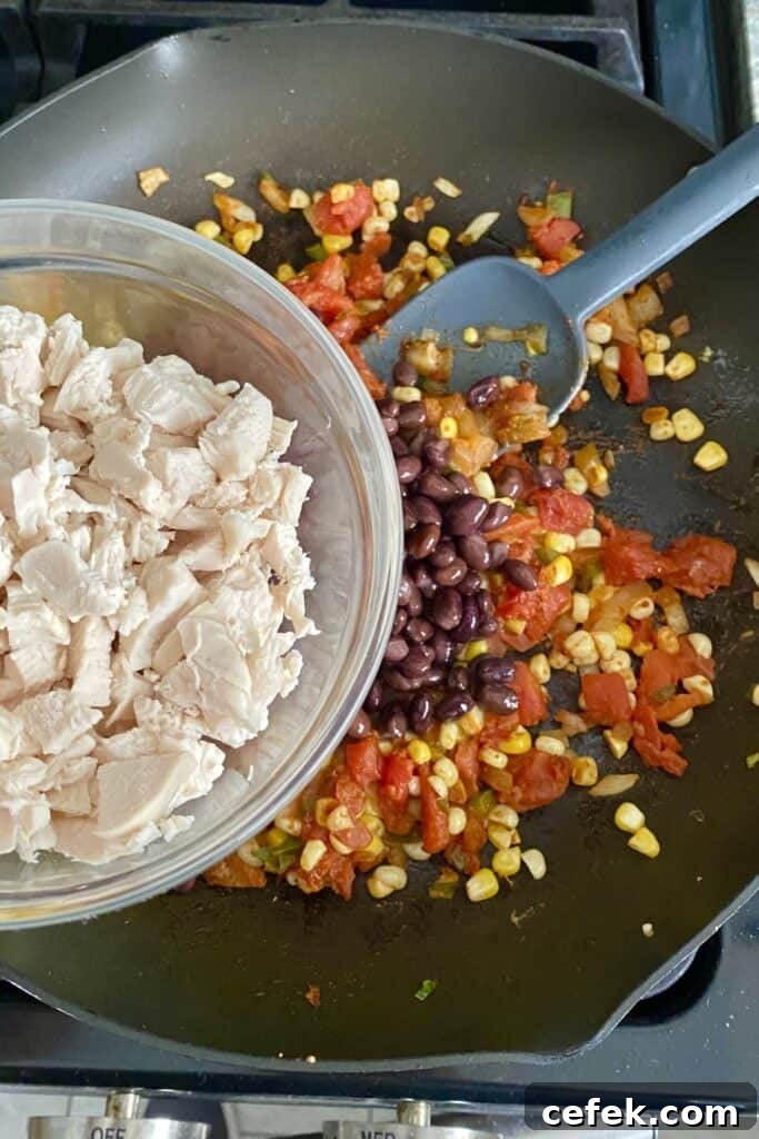 adding cooked chicken to tortilla stacks filling