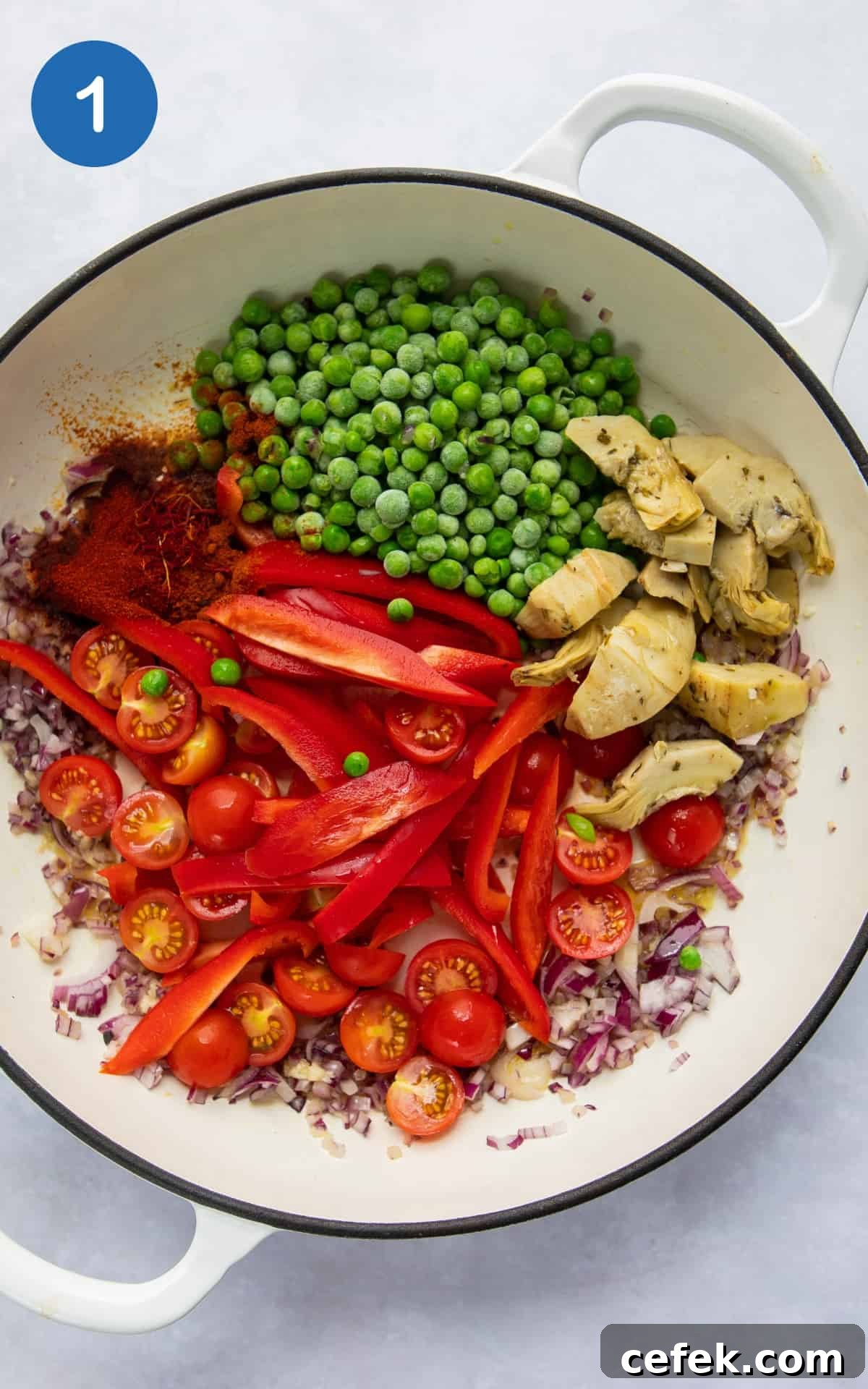 ingredients to make paella in large shallow white frying pan.