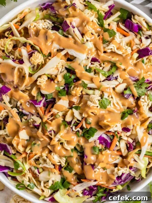 Ramen cabbage salad with peanut dressing over top in white bowl.
