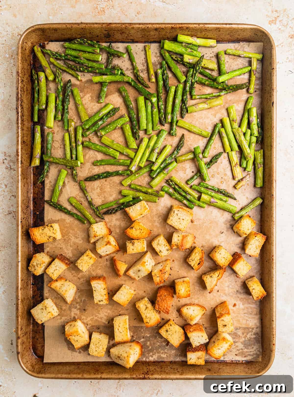 Baked sourdough croutons and asparagus on parchment lined sheet pan.