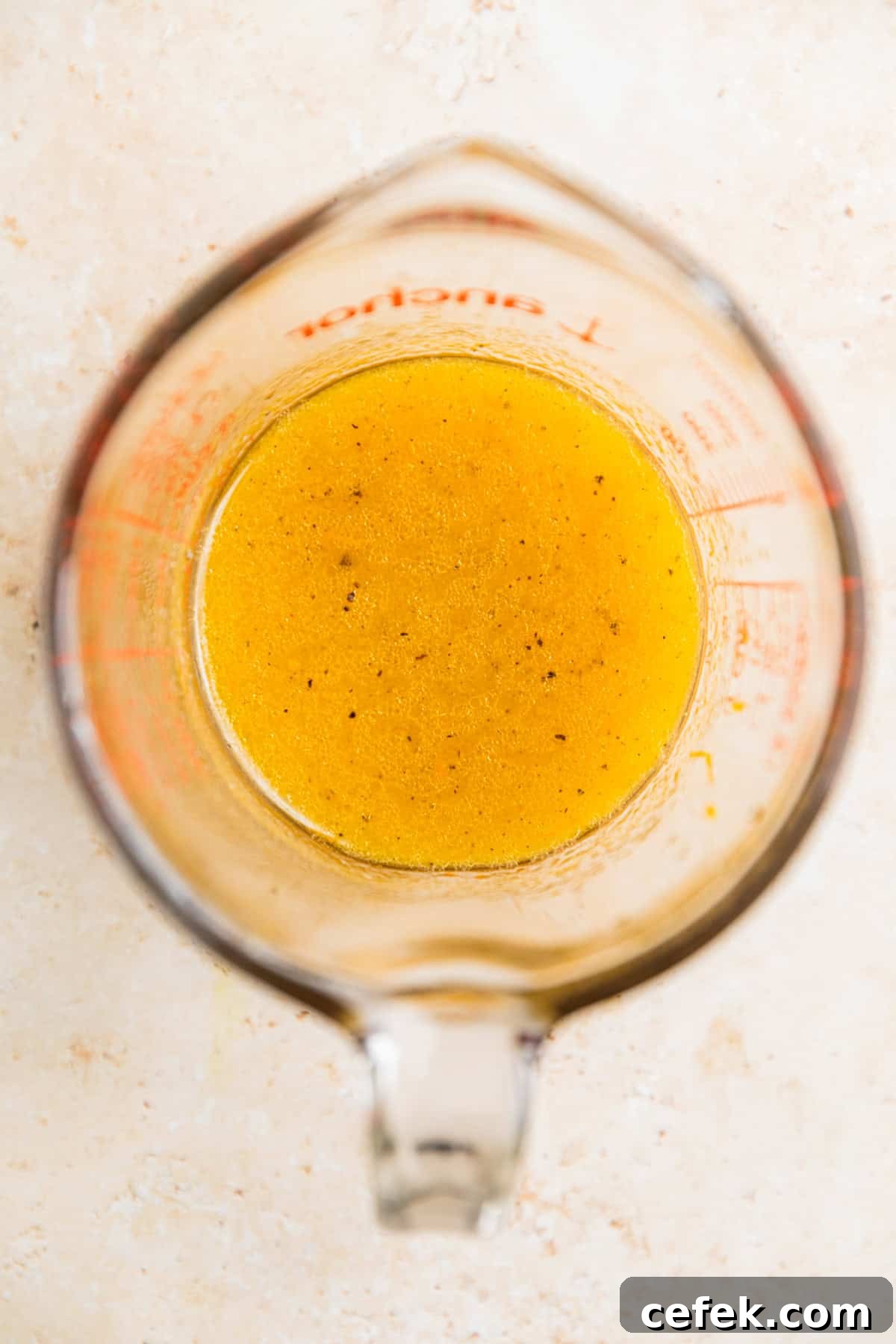 Honey citrus dressing in measuring glass cup.