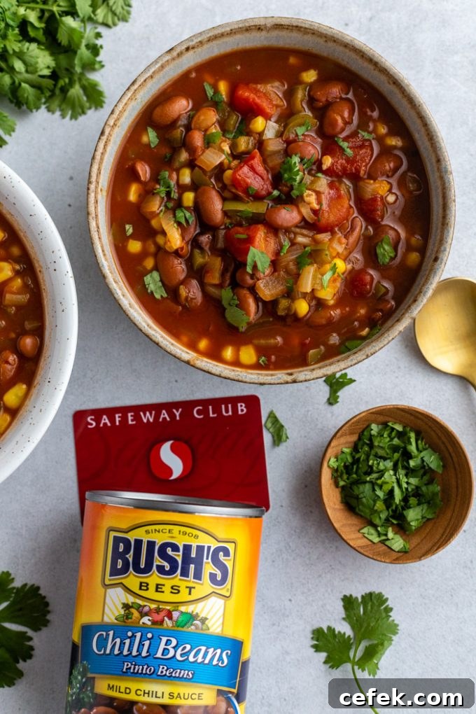 2 bowls of vegetarian chili with cilantro on the table next to it. A can of BUSH'S Chili Beans sitting next to it with a Safeway Club card as well