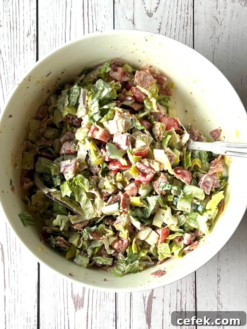 Chopped salad mixed with dressing in a medium bowl.