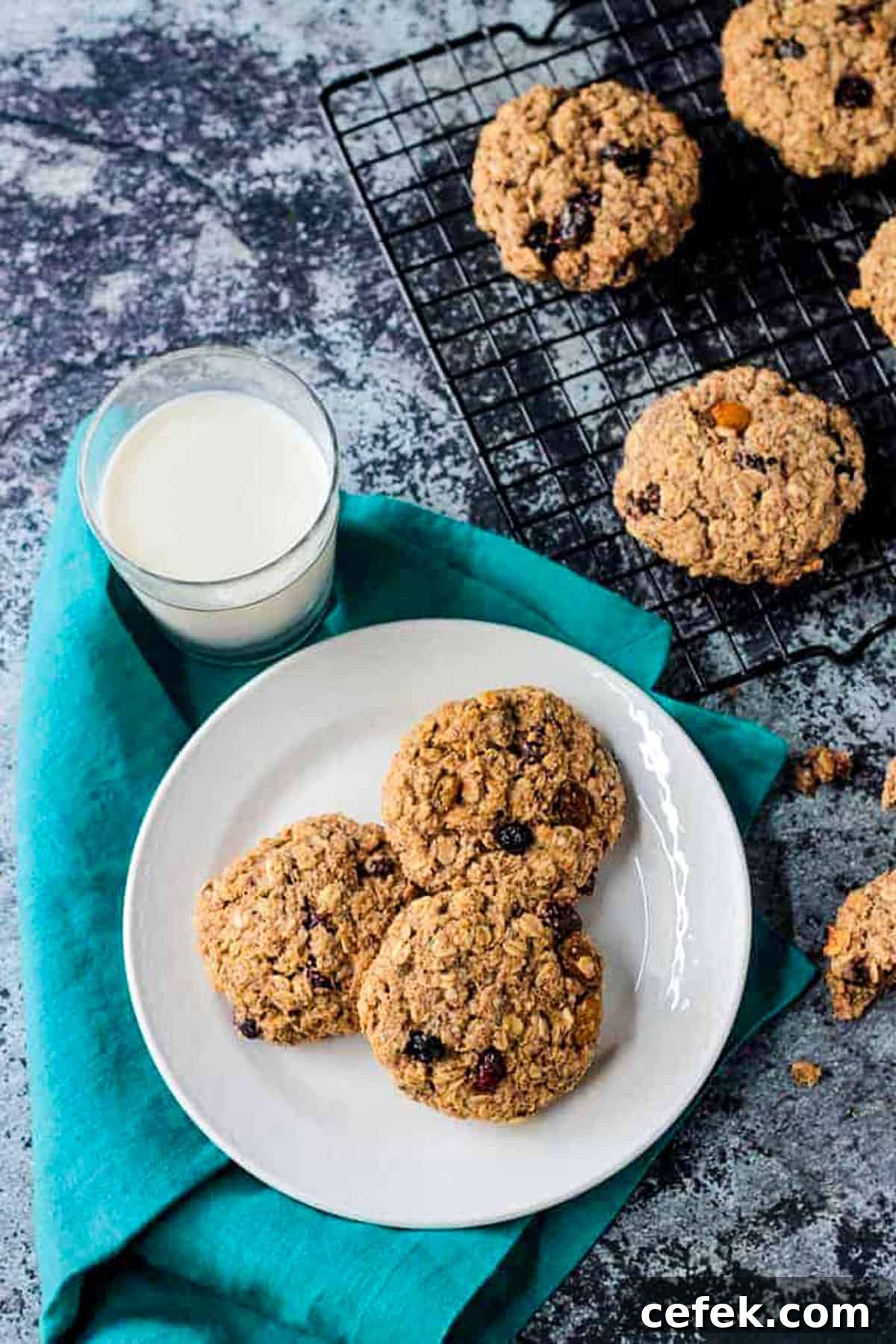 Three oatmeal breakfast cookies on a white plate next to a glass of milk.