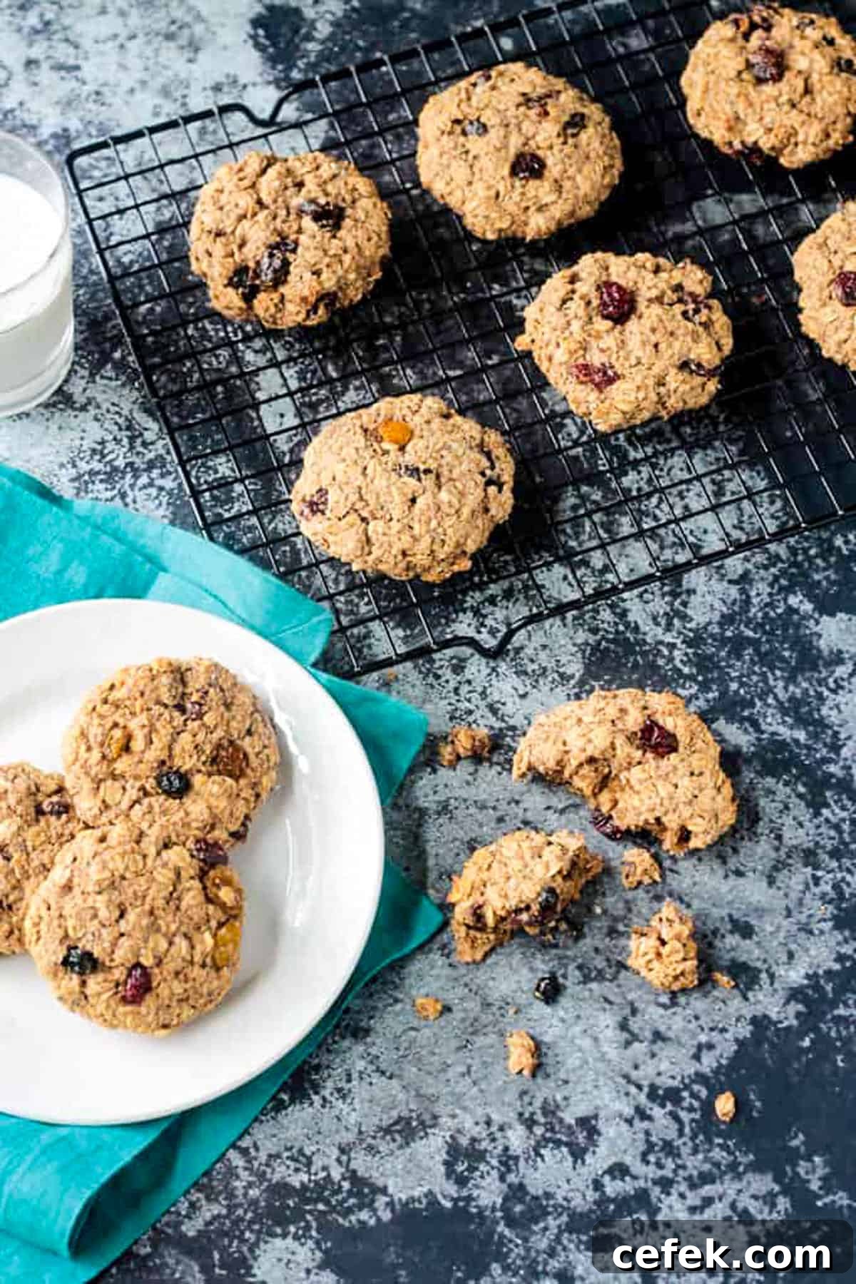One broken cookie on a table in front of a cooling rack of more.