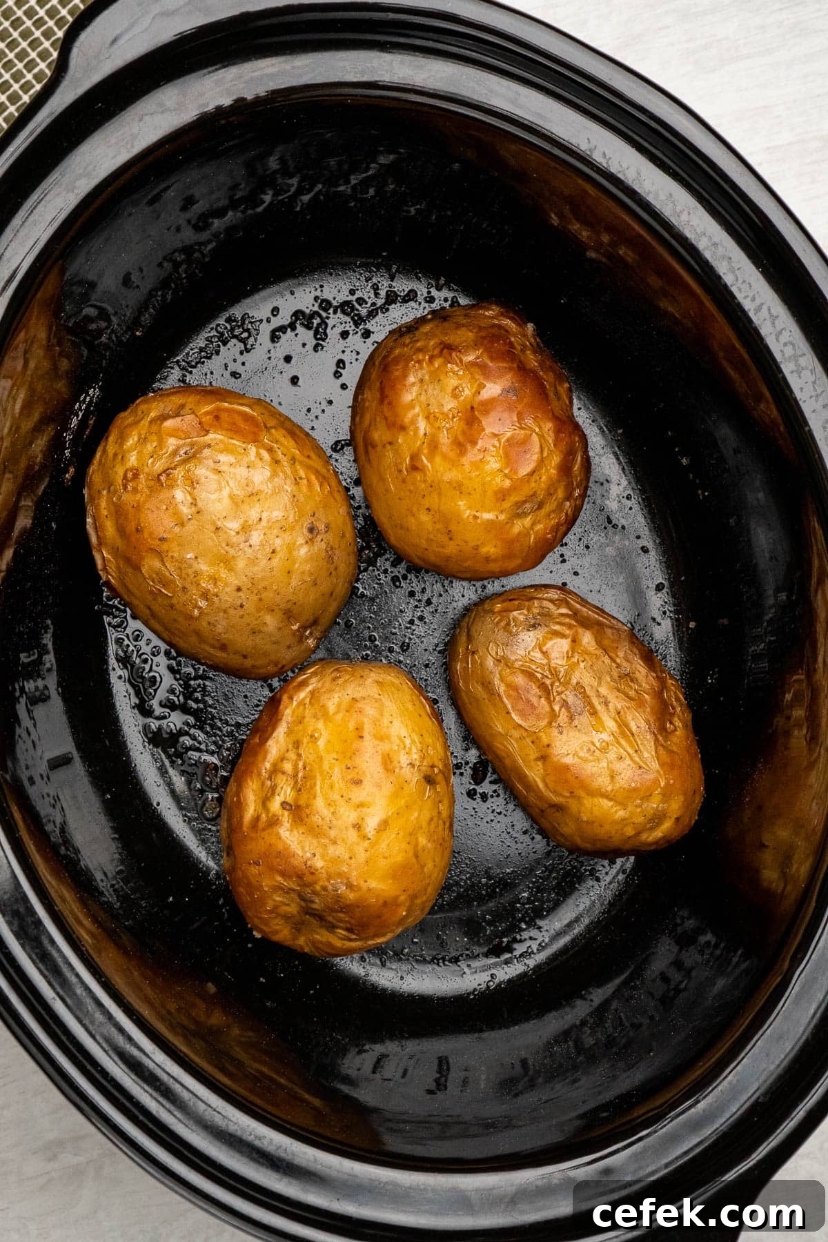 Four jacket potatoes cooked in a slow cooker, coated with oil and salt