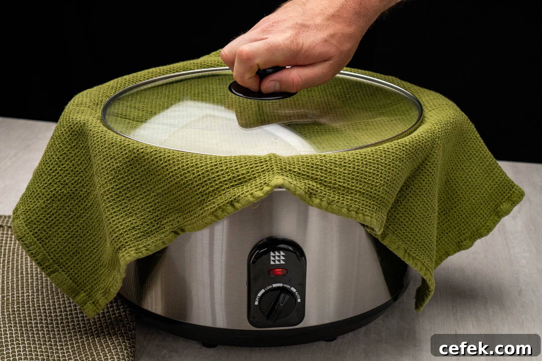 Placing the lid on top of a tea towel and slow cooker on high setting.