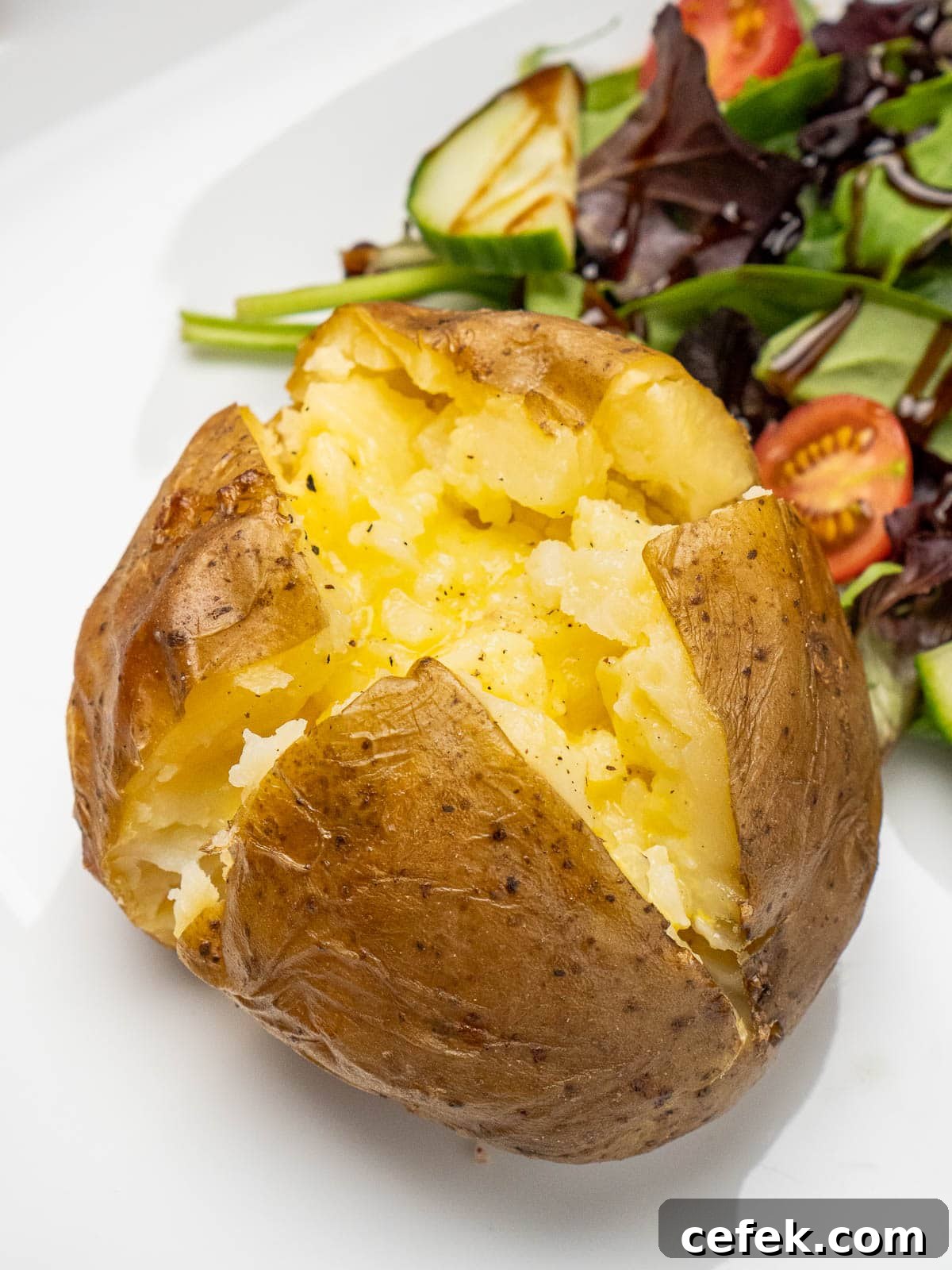 Slow Cooker Jacket Potato cut open with butter melted in the middle and a side salad.