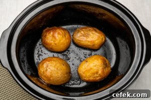 Four cooked jacket potatoes in a slow cooker