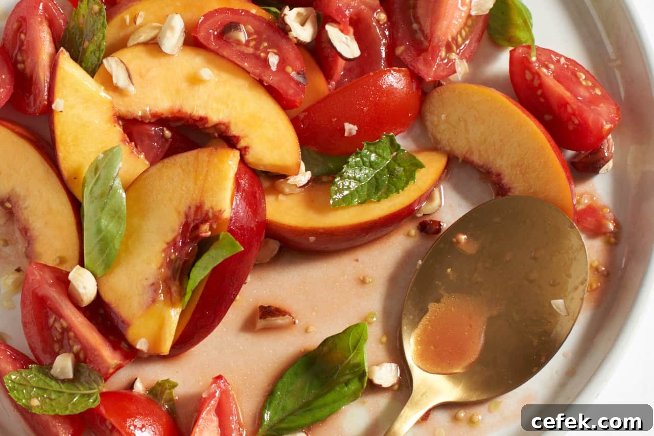 Nectarine salad with tomatoes and herbs on a white plate.