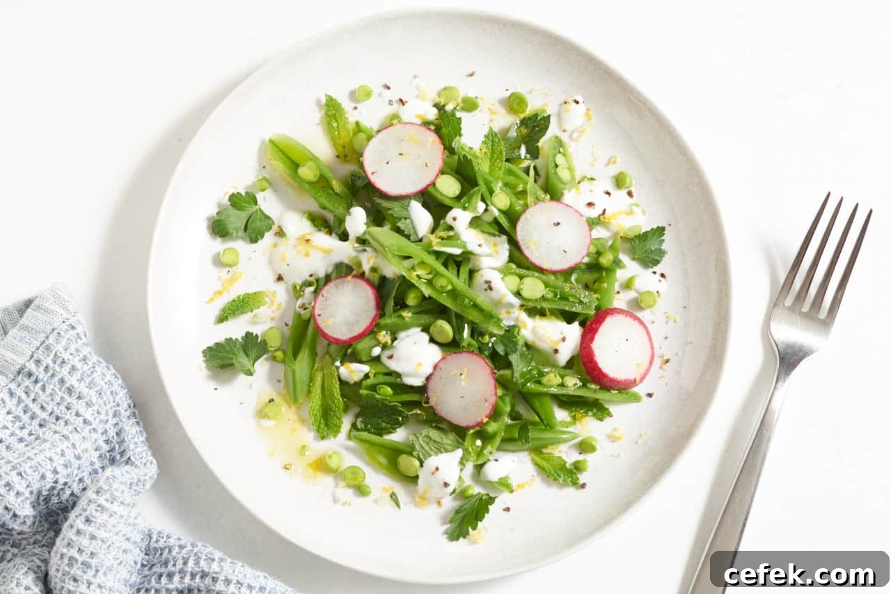 A plate of sugar snap pea salad topped with radishes and yogurt.