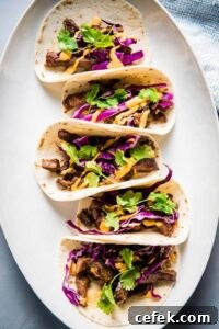Korean beef tacos on a white platter topped with red cabbage and Sriracha mayo