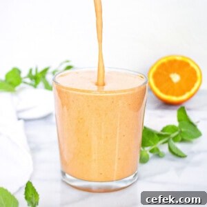 A smoothie being poured into a clear glass.