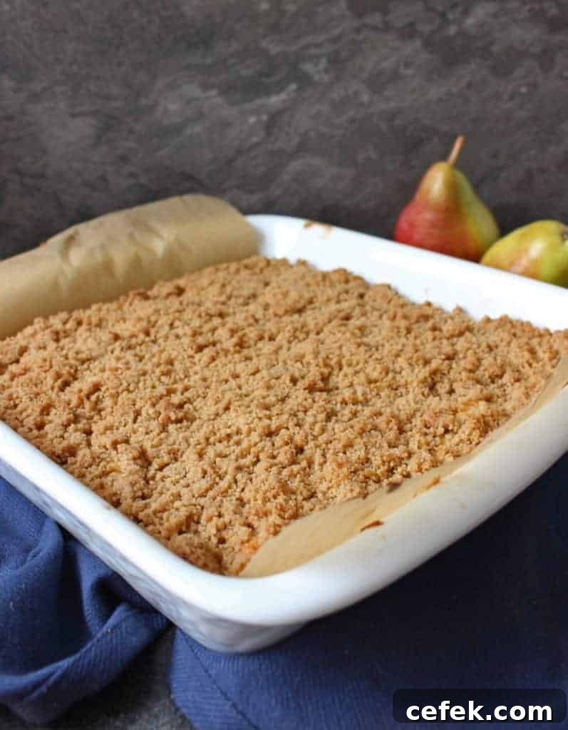 Pear Crumble Cake in a white ceramic dish over a navy napkin.