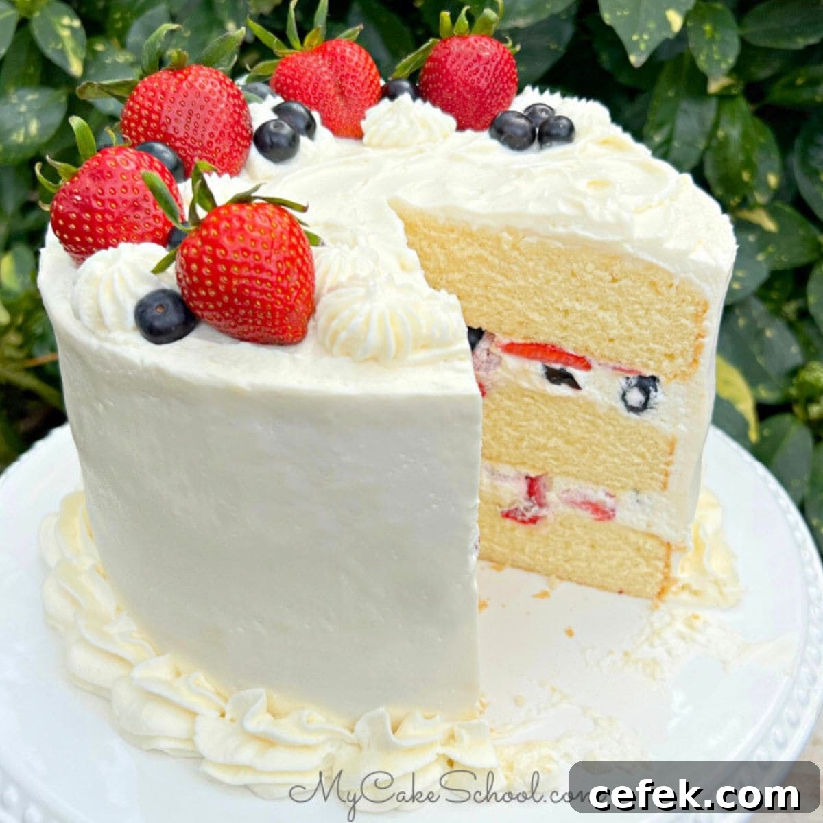 Moist Berry Chantilly Cake, sliced, on a cake pedestal.