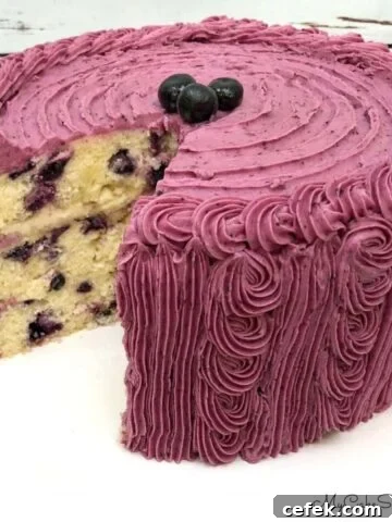 Lemon Blueberry Cake, sliced, on a cake pedestal.