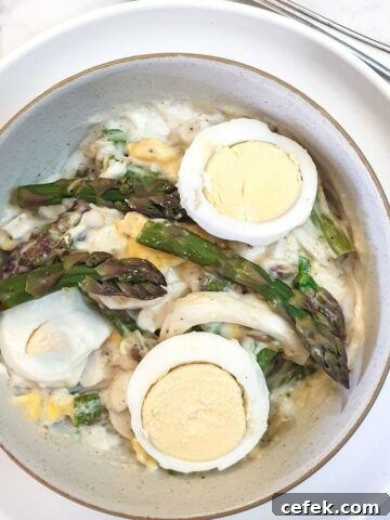 A dish of egg and asparagus salad garnished with additional sliced eggs and asparagus spears.