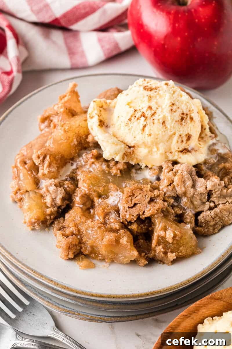 Apple Spice Dump Cake served on a stack of plates topped with vanilla ice cream.
