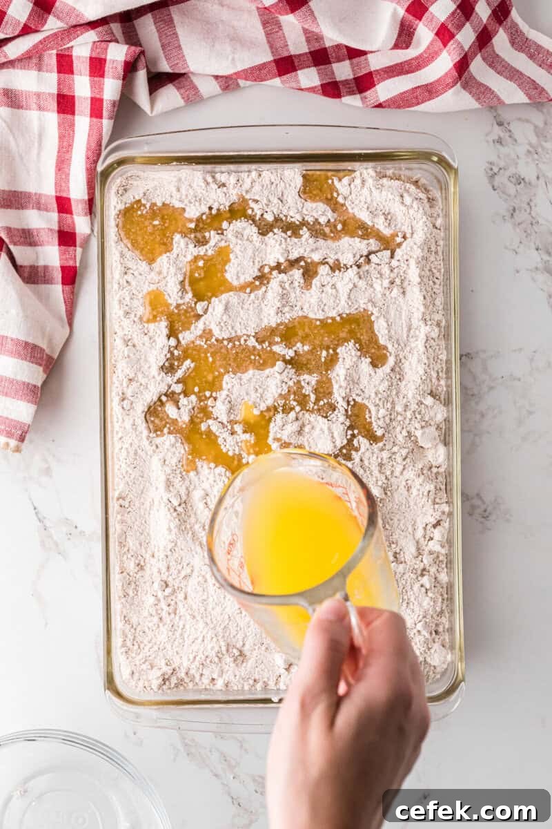 pouring the melted butter on top of the cake mix.