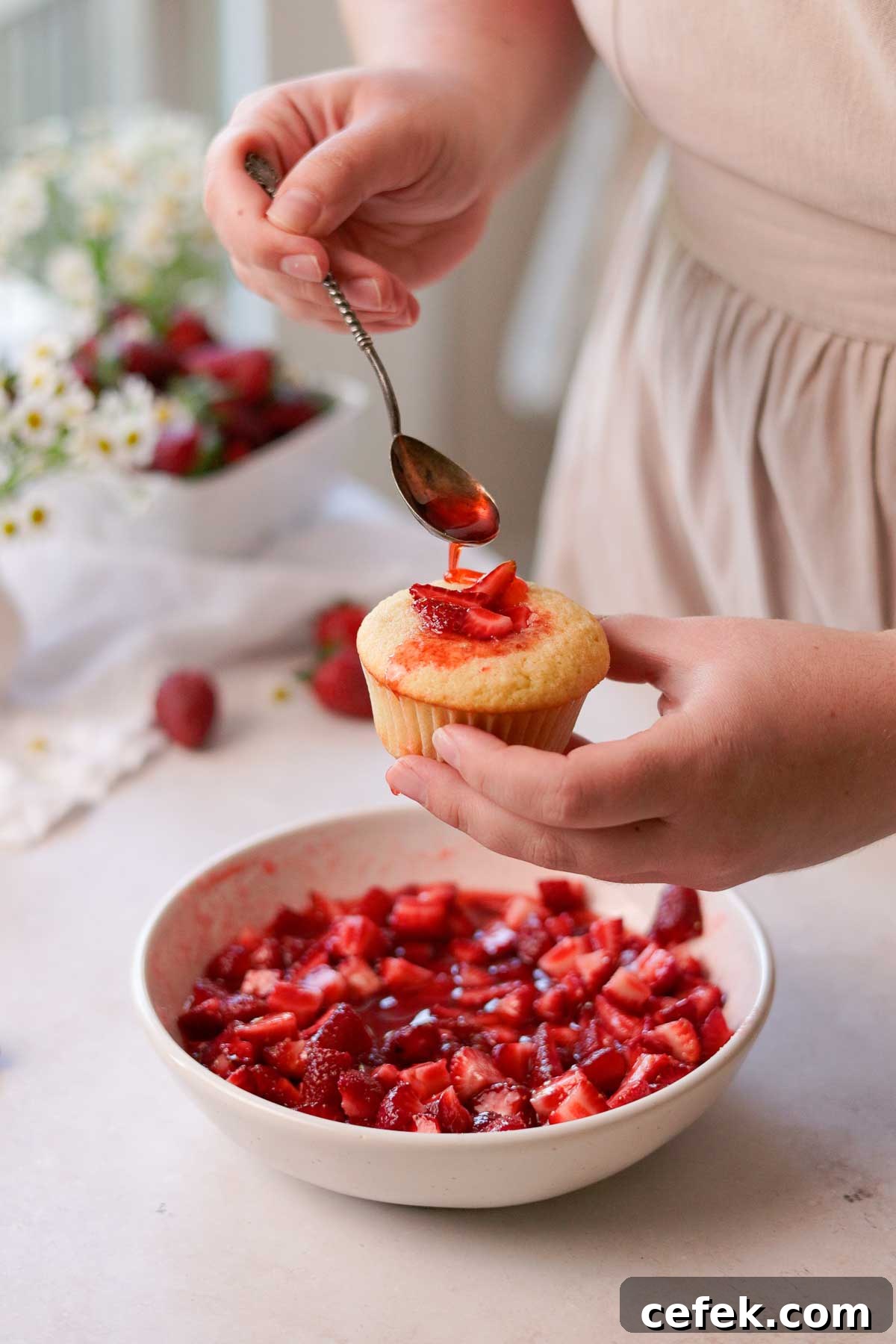 filling the cupcakes with fresh macerated strawberries and pouring the syrup on top