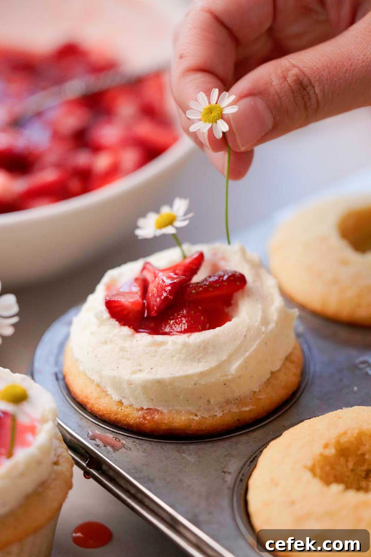 decorating the cupcakes with daisies and fresh cut strawberries