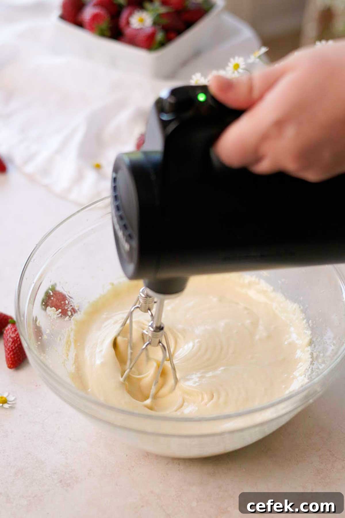 vanilla cupcake batter wet ingredients being mixed in a glass bowl with an electric mixer