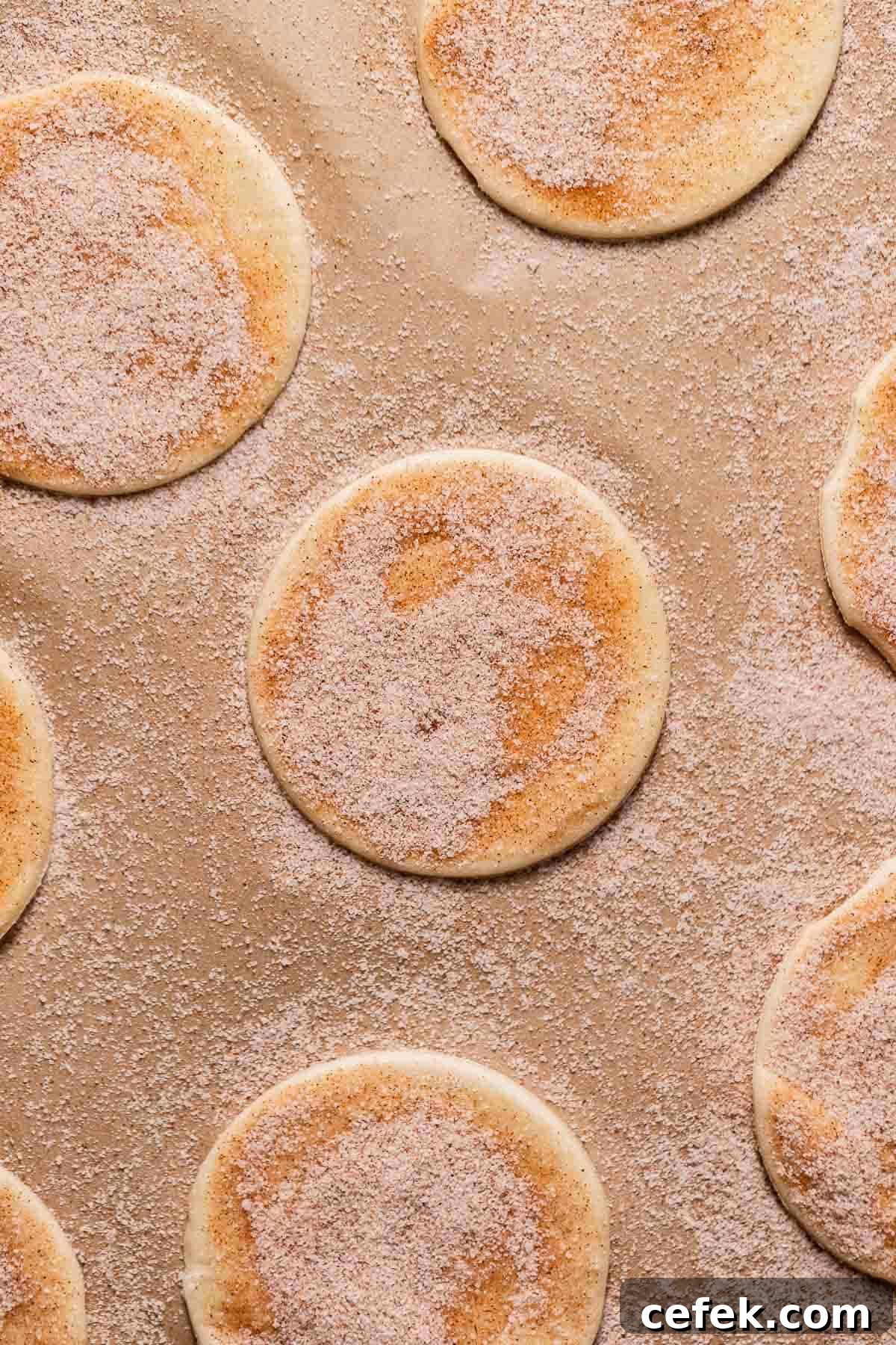 Puff pastry rounds on a baking sheet brushed with egg wash and sprinkled heavily with cinnamon sugar.